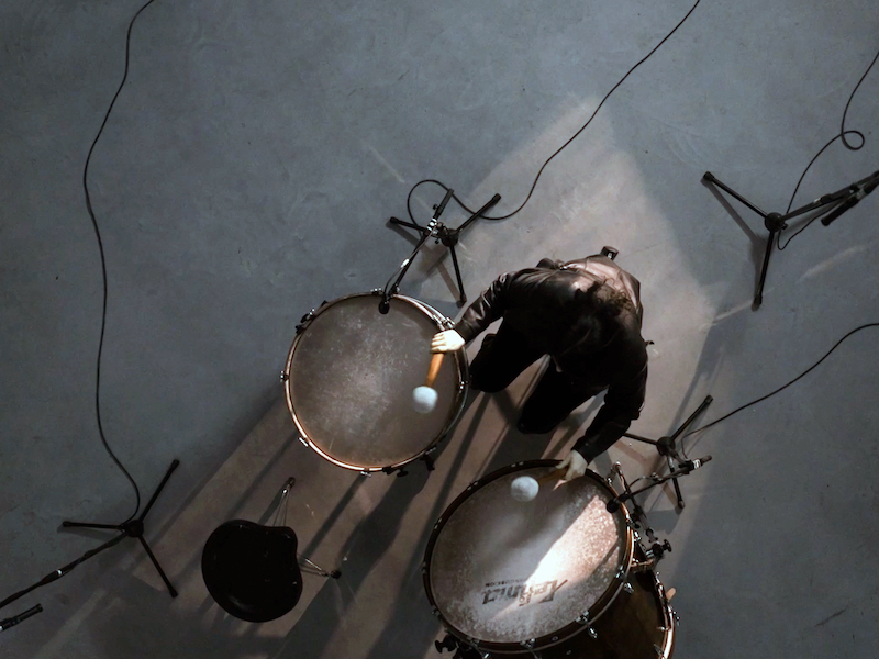 Photograph from a bird perspective showing a person playing drums with percussion mallets