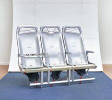 Photograph of an art installation with a row of three silver airplane seats