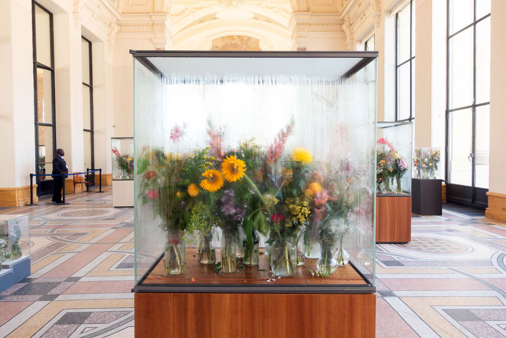 Art installation with bouquets including sunflowers in glass cabinets in the decorated entry hall of Petit Palais 