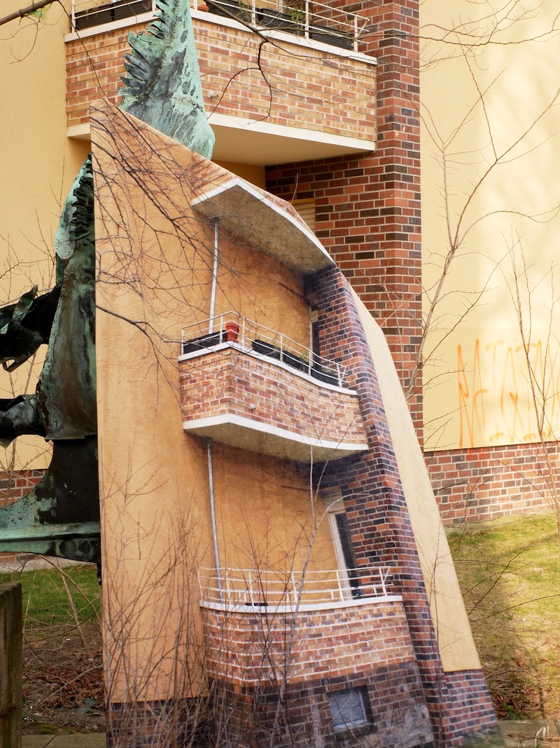 A poster or buildings' balconies in front of the actual building, poster is leaning on a statue 